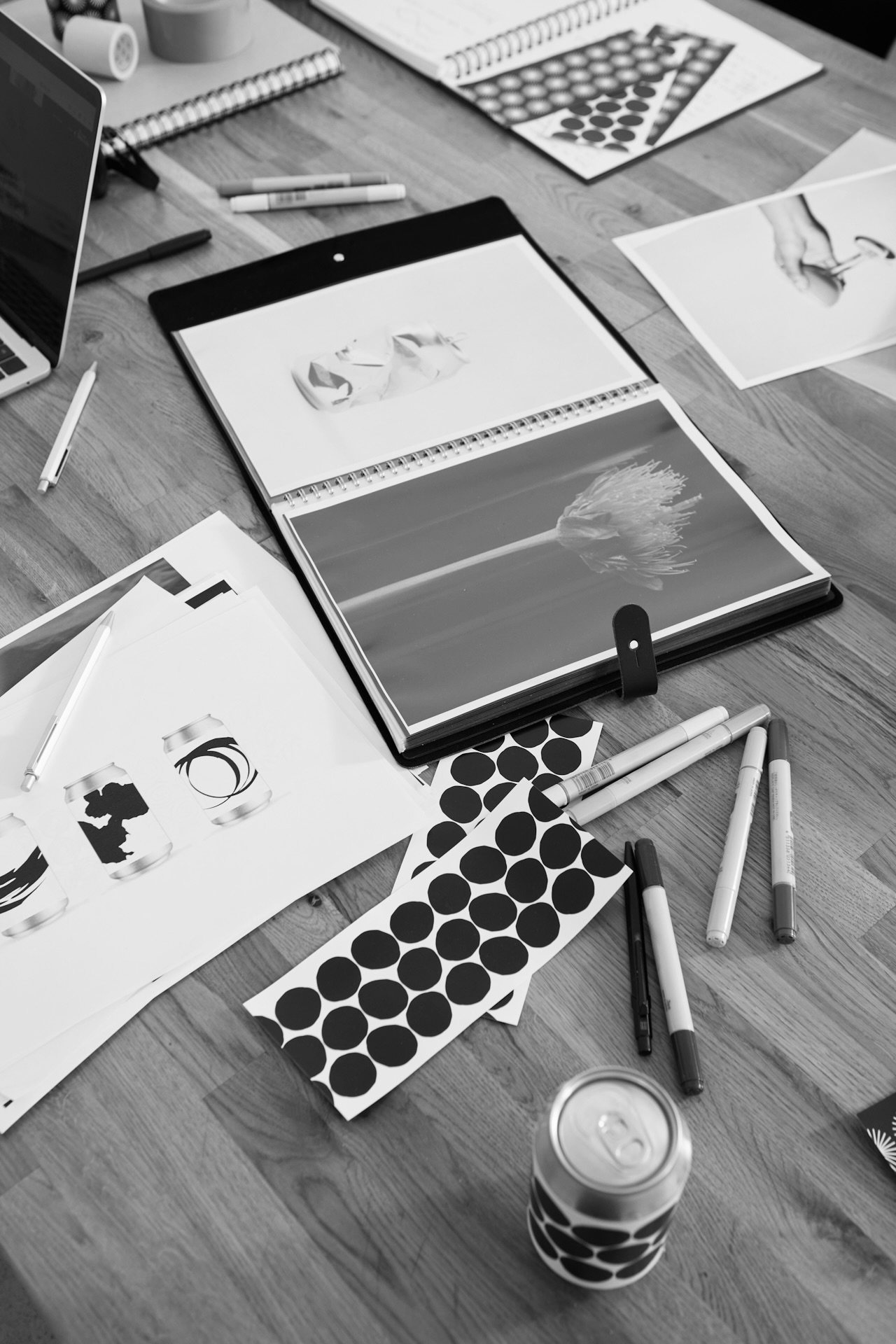 A creative's desk covered with sketchbooks, markers, and printed design work.